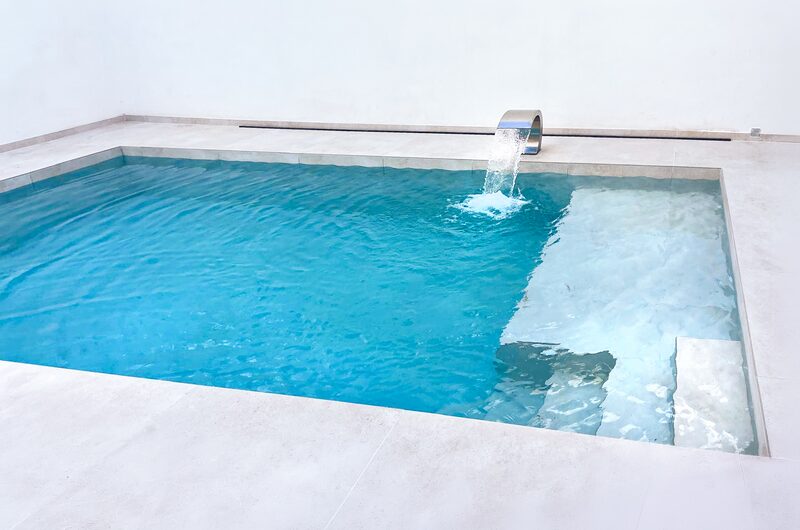 Piscina con cascada de acero inoxidable y escalera de obra de ancho completo