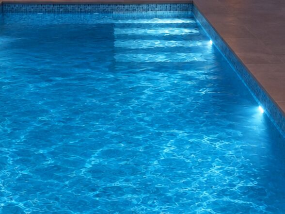 Piscina iluminada de noche con focos LED empotrados en el vaso